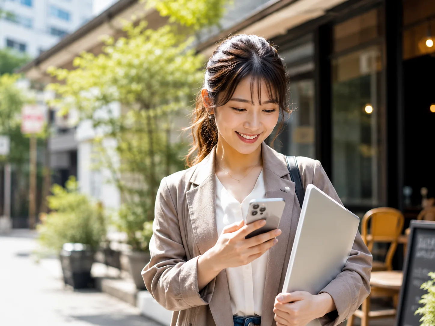 街中でスマホとノートパソコンを持つ女性